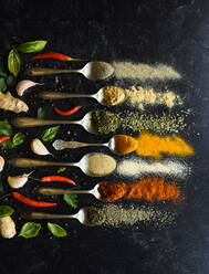 Overhead of spoons full of herbs and spices on a black background. - CAVF95804