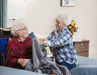 Senior woman covering man with blanket - TETF00386