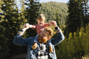 Father carrying his daughter on his shoulders by forest - TETF00407