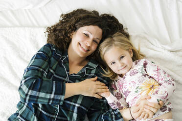 Hohe Winkelansicht von Mutter und Tochter im Pyjama auf dem Bett liegend - TETF00411