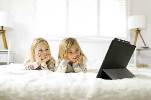 Mädchen, die im Bett liegend einen Film auf einem digitalen Tablet anschauen - TETF00413