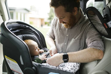 Vater schnallt kleinen Jungen (2-3 Monate) im Autositz an - TETF00418