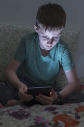 Junge (8-9) benutzt digitales Tablet im Bett - TETF00455