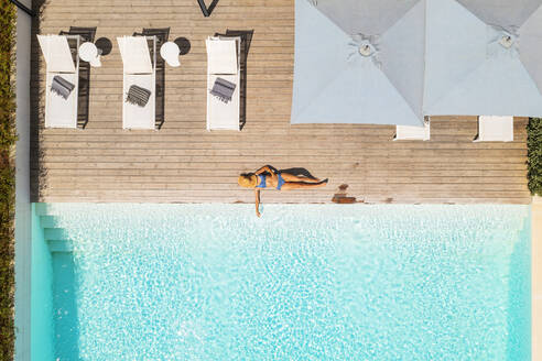 Aerial view of a blonde woman relaxing along the swimming pool of a luxury hotel, Beja, Portugal. - AAEF14232