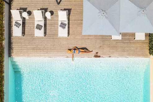 Luftaufnahme einer blonden Frau, die sich am Swimmingpool eines Luxushotels entspannt, Beja, Portugal. - AAEF14232