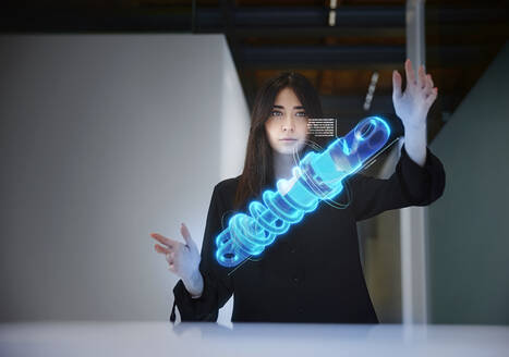 Female engineer analyzing shock absorber in mid-air at office - CVF01946