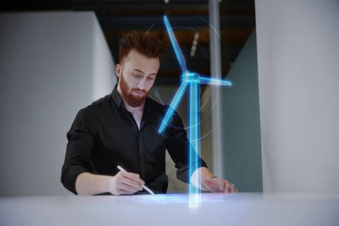 Ingenieur bei der Arbeit an einer digitalen Anzeige bei einer Windmühle am Schreibtisch im Büro - CVF01950