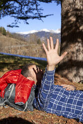 Mann gestikulierend Stoppschild unter Baum liegend an sonnigem Tag - VEGF05296