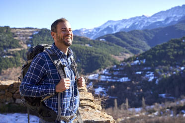 Cheerful man with eyes closed wearing backpack on sunny day - VEGF05311