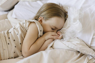 Girl with feather sleeping on bed at home - SEAF00611