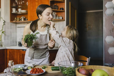 Mädchen füttert Mutter in der Küche zu Hause mit Essen - SEAF00627