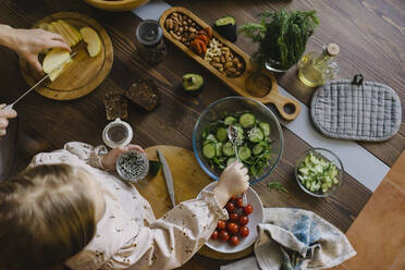 Mädchen macht Salat von Mutter Schneiden von Lebensmitteln in der Küche zu Hause - SEAF00630