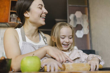 Fröhliche Mutter mit Tochter hält Nudelholz in der Küche - SEAF00636