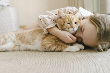 Girl with eyes closed hugging cat at home - SEAF00641