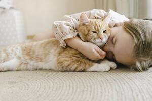 Mädchen mit geschlossenen Augen umarmt Katze zu Hause - SEAF00641
