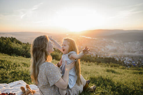 Glückliche Mutter und Tochter verbringen Zeit miteinander bei Sonnenuntergang - VBUF00033