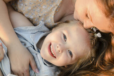 Mother kissing cute daughter on sunny day - VBUF00039