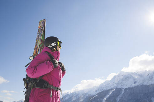 Mann in warmer Kleidung mit Blick auf einen Berg an einem sonnigen Tag - OMIF00712