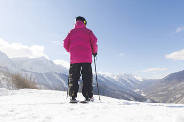 Mann mit Skistöcken und Blick auf einen Berg, der im Winter im Schnee steht - OMIF00723