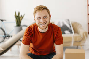 Happy young man sitting at home - XLGF02798