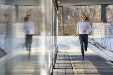 Frau in Sportkleidung joggt auf dem Fußweg - STSF03149