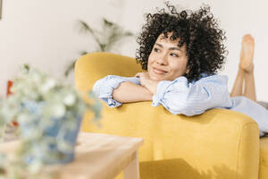 Lächelnde nachdenkliche Frau auf dem Sofa im Wohnzimmer zu Hause - XLGF02815