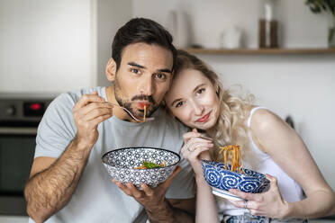 Smiling man and woman eating spaghetti at home - PESF03492