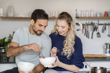 Lächelnde junge Frau teilt Essen mit ihrem Freund in der Küche zu Hause - PESF03496