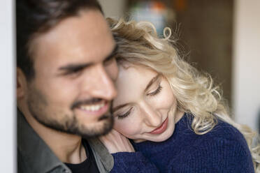 Smiling young woman with blond hair embracing boyfriend - PESF03518