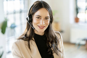 Smiling businesswoman wearing headset at home office - DMOF00281