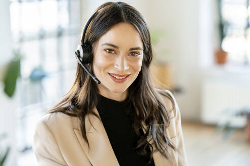 Lächelnde Geschäftsfrau mit Headset im Heimbüro - DMOF00281