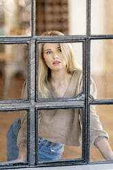 Beautiful blond woman seen through glass window - DMOF00294