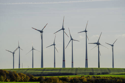 Hoch aufragende Windturbinen in sonniger ländlicher Umgebung, Deutschland - FSIF05931