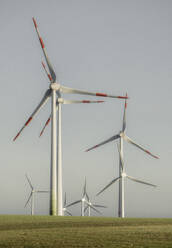 Windkraftanlage in einem sonnigen ländlichen Gebiet vor blauem Himmel, Deutschland - FSIF05936