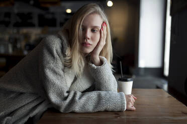Junge Frau sitzt am Cafétisch - TETF00663