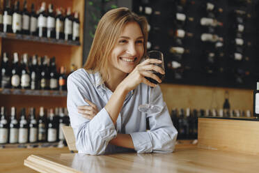 Lächelnde junge Frau hält ein Glas Rotwein - TETF00698