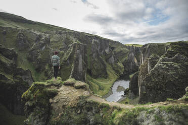 Junger Mann steht auf einer Klippe über einer Schlucht in Kirkjubµjarklaustur, Island - TETF00743