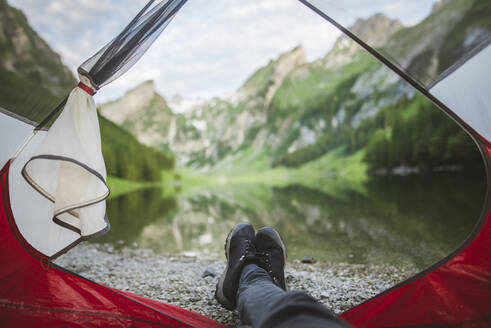 Die Füße einer Frau ragen aus dem Zelt am Seealpsee in den Appenzeller Alpen, Schweiz - TETF00747