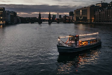 Beleuchtetes Boot auf dem Fluss in der Abenddämmerung - MJRF00640