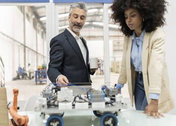 Ingenieur bespricht das Modell eines Roboterfahrzeugs mit einem Entwickler in der Fabrik - JCCMF05584