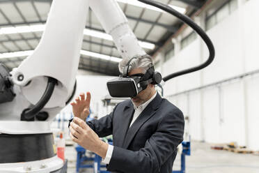 Geschäftsmann in virtueller Realität gestikuliert in einer Fabrik - JCCMF05599