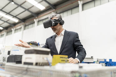 Businessman wearing virtual reality standing in factory - JCCMF05601
