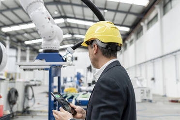 Ingenieur prüft Roboterarm über Tablet-PC in der Fabrik - JCCMF05604