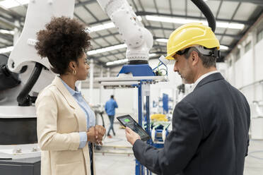 Engineer holding tablet PC standing with developer in factory - JCCMF05610