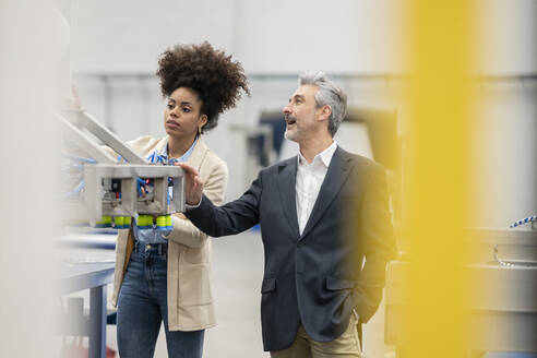 Ingenieure, die eine Maschine analysieren, arbeiten in einer Fabrik zusammen - JCCMF05627