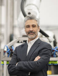 Businessman standing with arms crossed in at factory - JCCMF05632