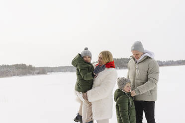 Mann und Frau mit Söhnen stehen im Winter im Schnee - SEAF00664