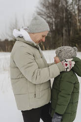 Lächelnder Vater hilft seinem Sohn im Winter mit der Kapuze - SEAF00677