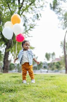 Nettes kleines Mädchen mit Luftballons im Park stehend - PGF01035