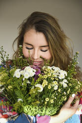 Lächelnde Frau, die an einem Blumenstrauß riecht - VBUF00060